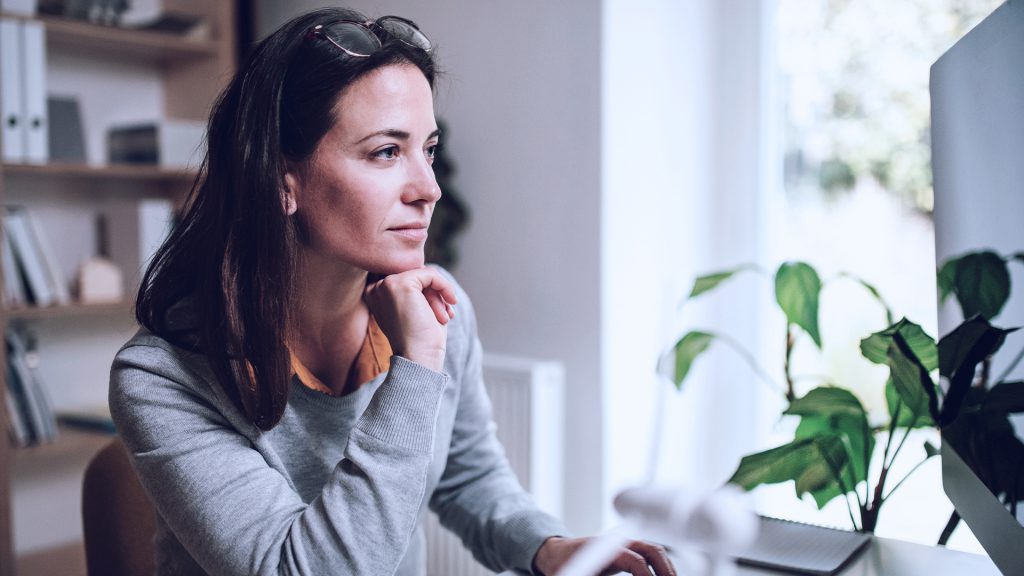 Mulher olhando para uma tela de computador, pensando sobre a sustentabilidade empresarial.